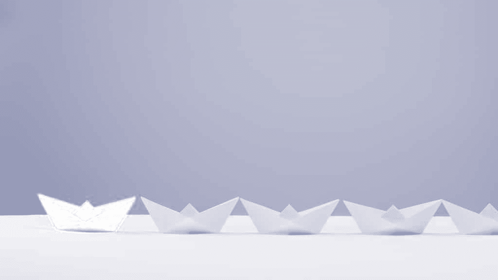 Leadership concept. Red paper ship leading among white